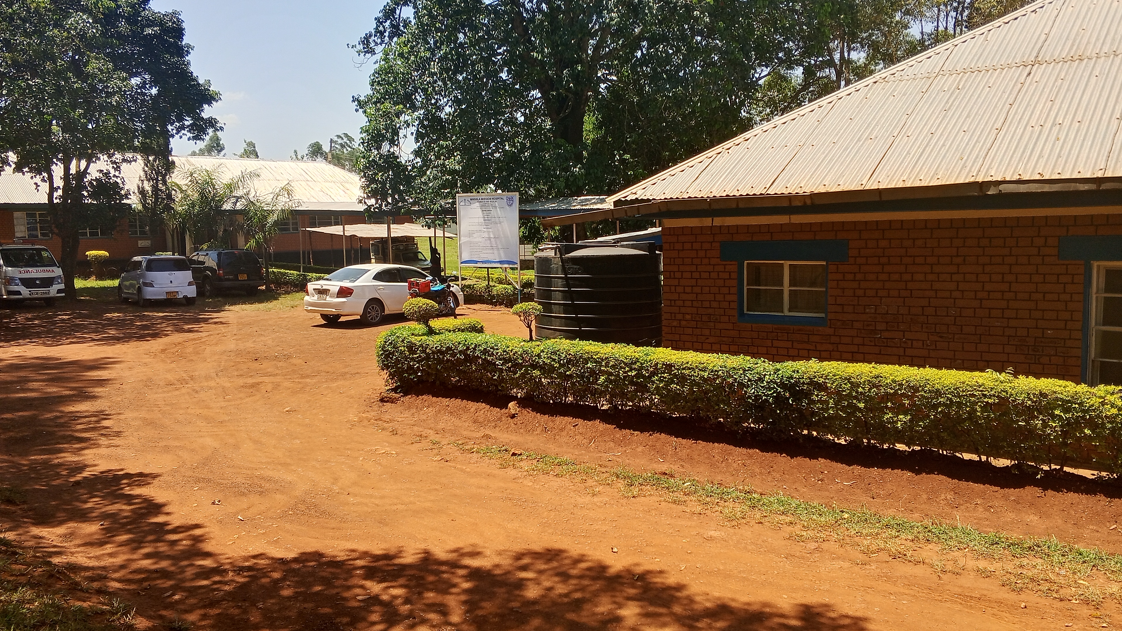 Mwihila Mission Hospital main facility with well-maintained grounds and parking area